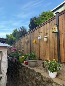 Vertical cedar fence with plantings along a retaining wall