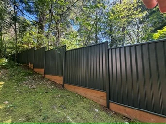 Durabond steel panel fence stepped down a wooded slope